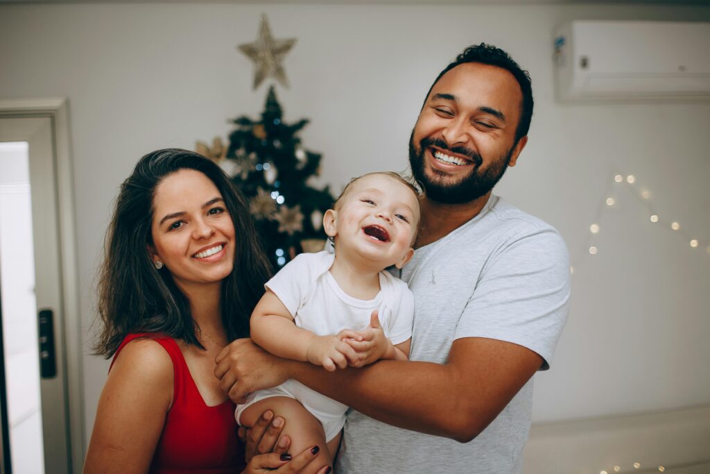Smiling family enjoying festive Christmas moments indoors with a decorated tree.